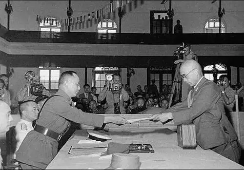 上圖：日本中國派遣軍參謀長小林淺三郎（右）向中國陸軍總司令何應欽呈遞《降書》。(資料圖片)