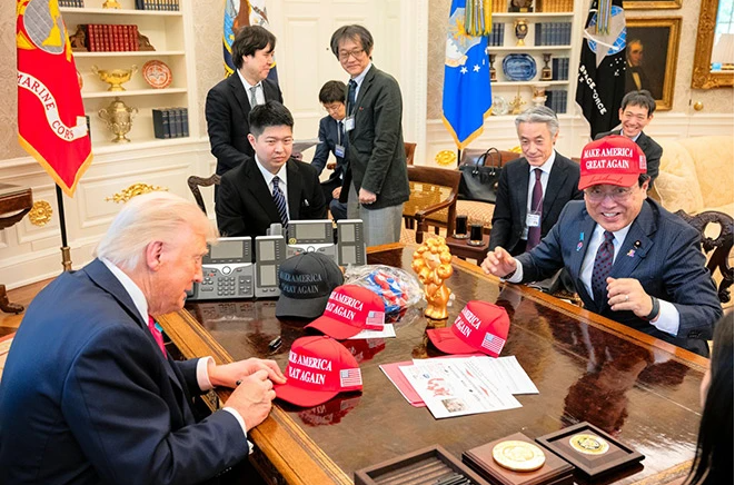 美日首輪貿易談判前，特朗普將一頂印有“Make America Great Again”的紅帽子贈予赤澤亮正（右），赤澤當場戴上紅帽，滿臉堆笑。（新華網）