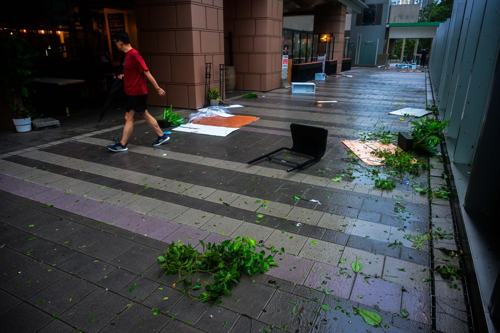 行人經過香港一處人行天橋上被風吹落的支架。(新華社)