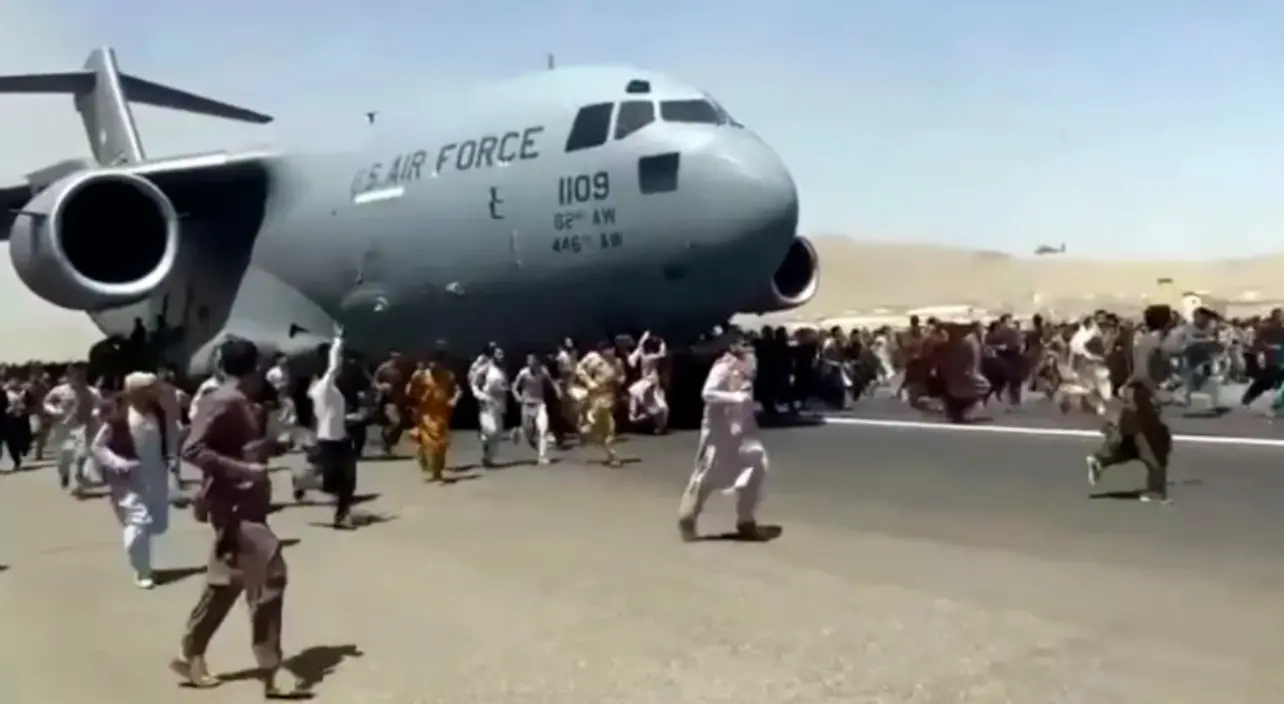 2021年8月16日，一架美軍C-17運輸機沿著喀布爾機場跑道滑行，人們在旁邊奔跑。 視頻截圖